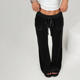 Person wearing black wide-leg pants and a white top on a light gray background